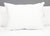 A large Envirosleep Dream Surrender Polyester Pillow by Manchester Mills, offering medium support, is upright on a tidy white bed with a gray headboard. The clean, fluffy pillow features a small tag on the right side in a minimal setting.